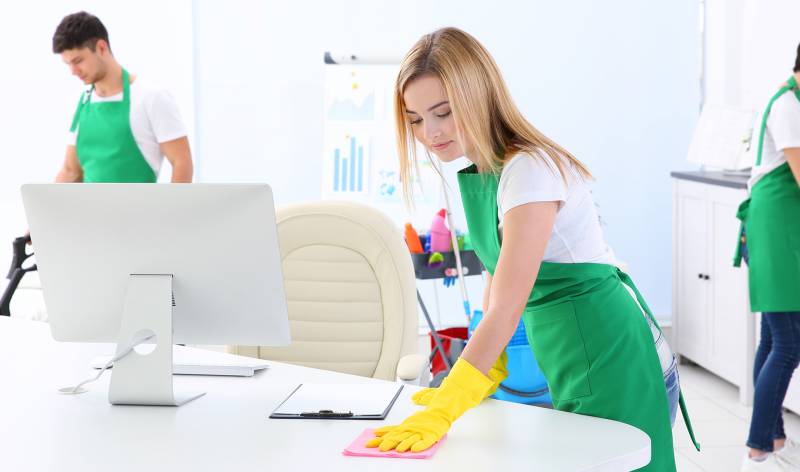 Woman scrubbing table inside a office