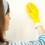 Woman in yellow gloves scrubbing wall
