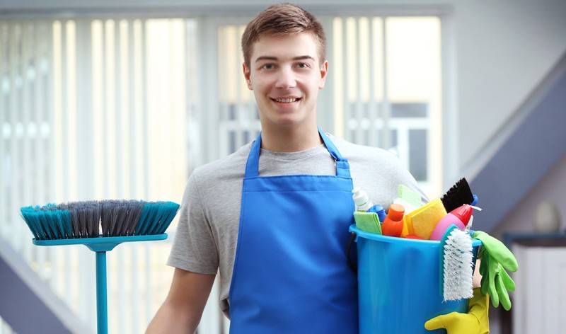A Man is standing with a basket with full of tools and wiper in his hand