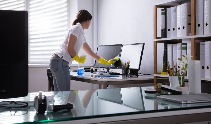 Woman in t-shirt and jeans holding spray bottle in hand and scrubbing system with cloth