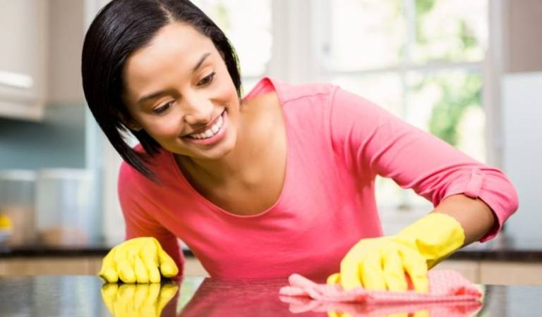 Woman in red dress and yellow gloves scrubbing a surface with red cloth