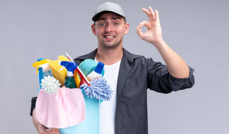 Man in cap and check shirt holding a blue basket filled with tools.