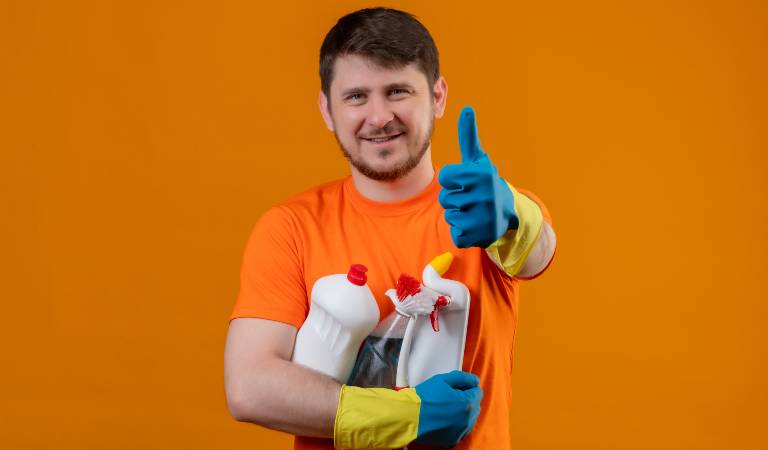 Man in orange top showing thumps up and holding bottles.