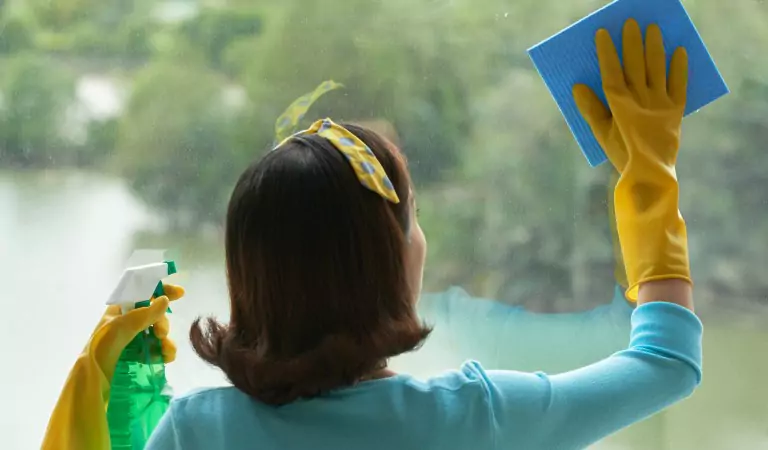 young woman wiping a window glass with a mop