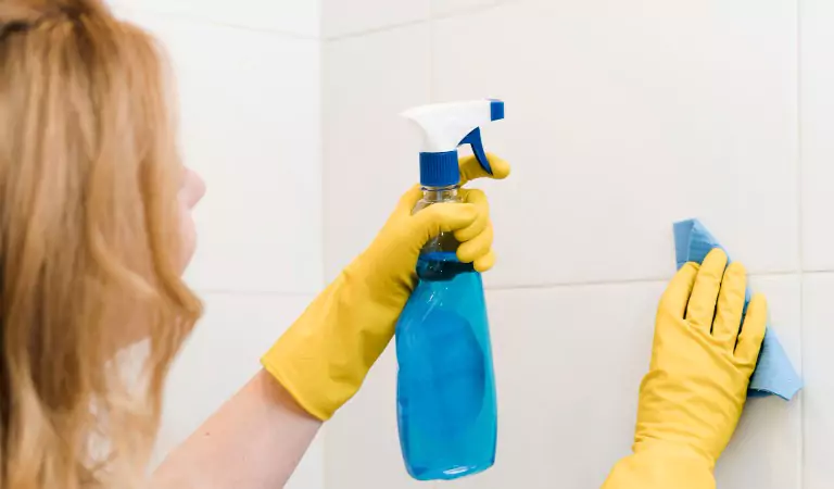young woman cleaning tiles inside of a bathroom