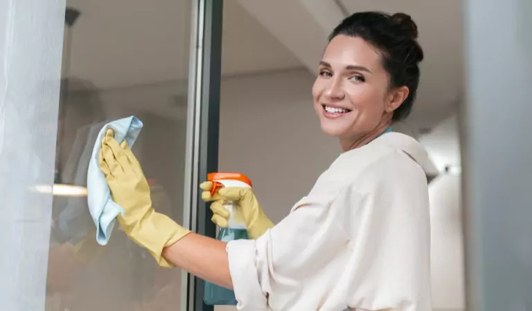 young woman wiping a door glass with a mop