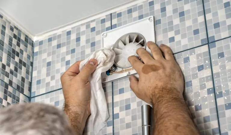 person cleaning a bathroom exaust