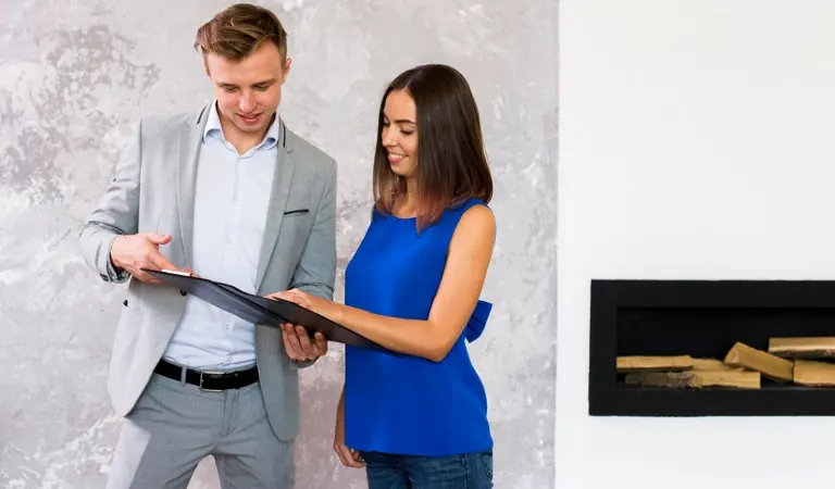 Woman in blue top discussing something with her owner holding a file in his hand.