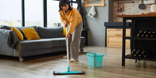 A lady is mopping hardwood floor inside her living room.