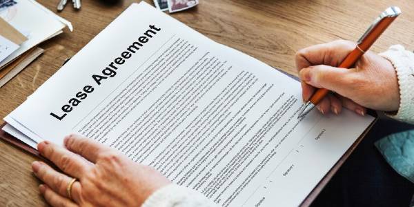a person is signing a lease agreement with a pen
