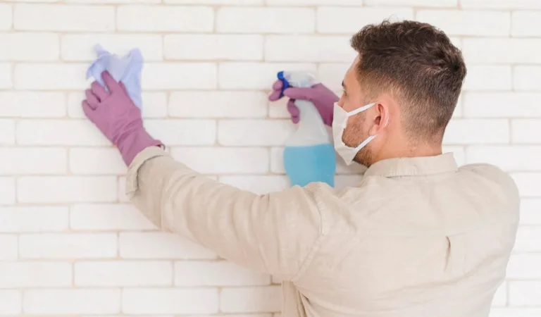 Man holding a cleaning spray cleaning wall with a cloth.