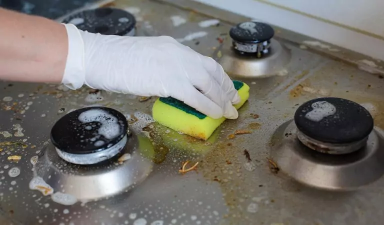 cropped picture of a person cleaning a stove