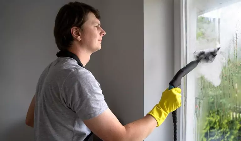 woman cleaning window glass with steam cleaner