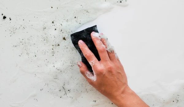 view of hand scrubbing dirt with sponge