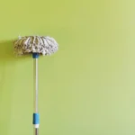 Close-up of mop laying on green wall