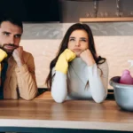 Wondering couple doing house cleaning in modern kitchen at home.Photo of young man and pretty woman washing with detergent and with wife.