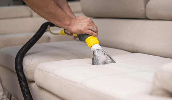 Cleaning a dirty sofa with a sofa washer close up of hands holding sofa cleaner professional