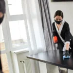 Professional cleaning service company employees in rubber gloves remove dirt from countertop in flat disinfection and steriles