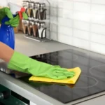 Woman cleaning stove at kitchen