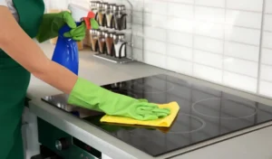 Woman cleaning stove at kitchen