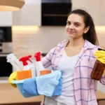 Woman in rubber protective yellow gloves holding cleaning tools house chores