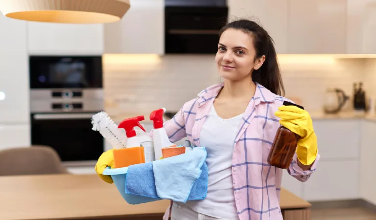 Woman in rubber protective yellow gloves holding cleaning tools house chores