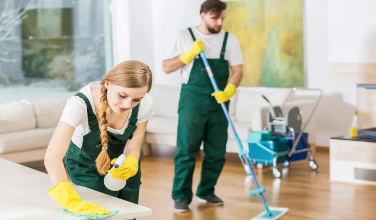 A couple cleaning a room with a mop and a painting on the wall