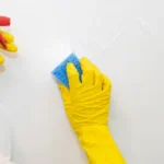Hands in yellow rubber gloves washing the walls