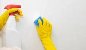 Hands in yellow rubber gloves washing the walls