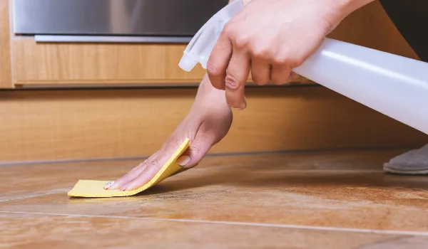 A person cleaning ceramic floor with special spray