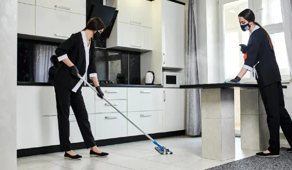 Professional cleaning service company employee in rubber gloves with a mop removes dirt from the floor