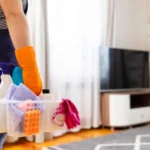 Woman in rubber gloves with basket of cleaning supplies ready to clean up